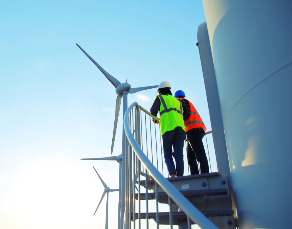 Two employees looking at a wind turbine